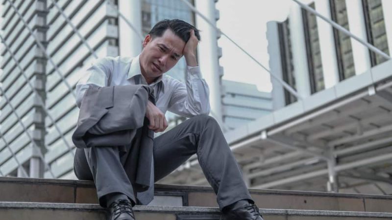 Distressed businessman outside buildings